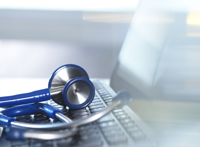 A laptop and a stethoscope slightly blurred