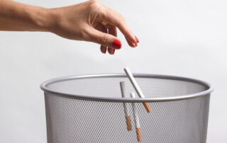 hand throwing unused cigarettes in the bin.  The beginning of giving up nicotine and becoming a non smoker on medical advice