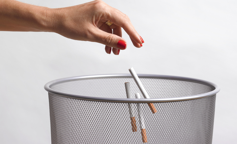 hand throwing unused cigarettes in the bin.  The beginning of giving up nicotine and becoming a non smoker on medical advice