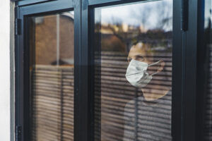 Man wearing a mask looking out of window