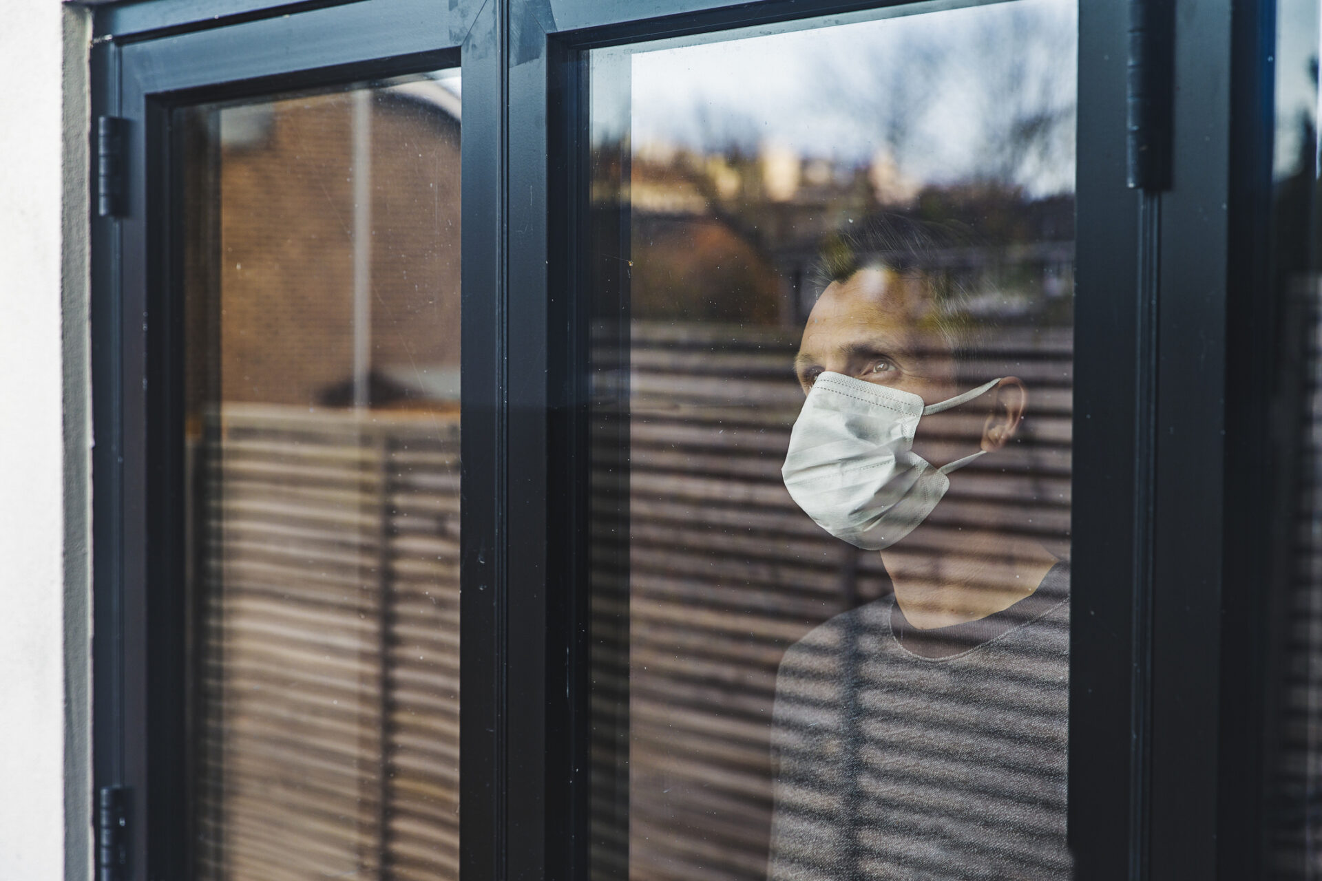 Man wearing a mask looking out of window