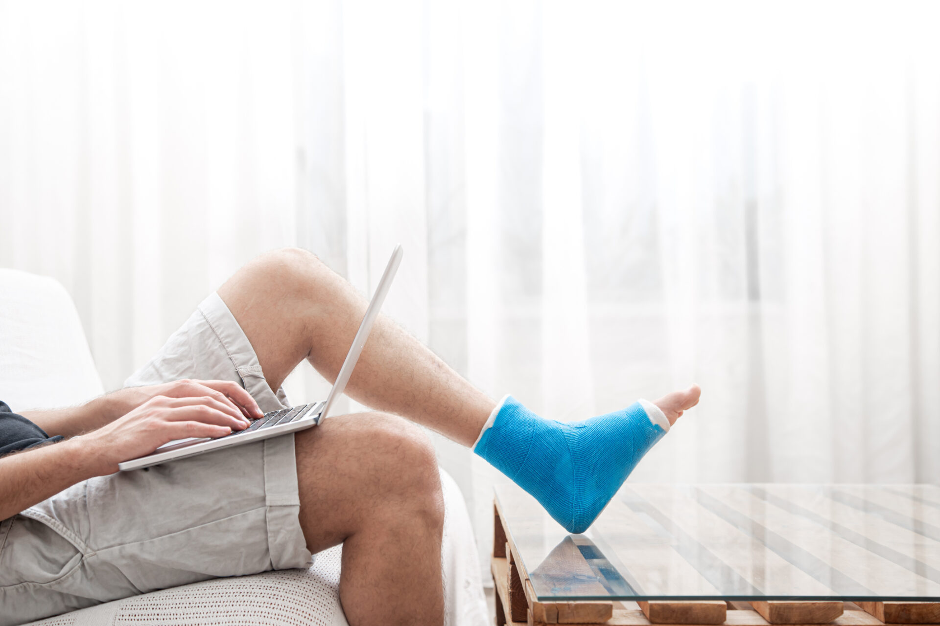lower half of man sat on sofa with ankle cast