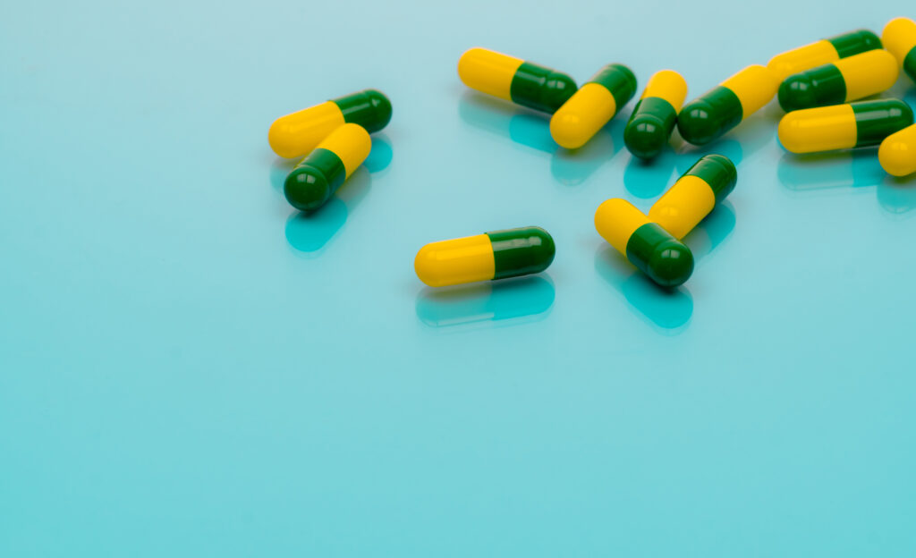 Tramadol pills Green-yellow capsule pills on blue background Tramadol is a strong painkiller medicine used to treat moderate to severe pain Background for tramadol misuse topics Opioids drug