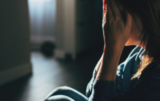 Silhouette of sad and depressed woman sitting on the floor at home