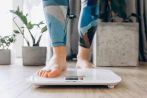 Close-up of bare feet stepping onto a digital scale in a modern home setting