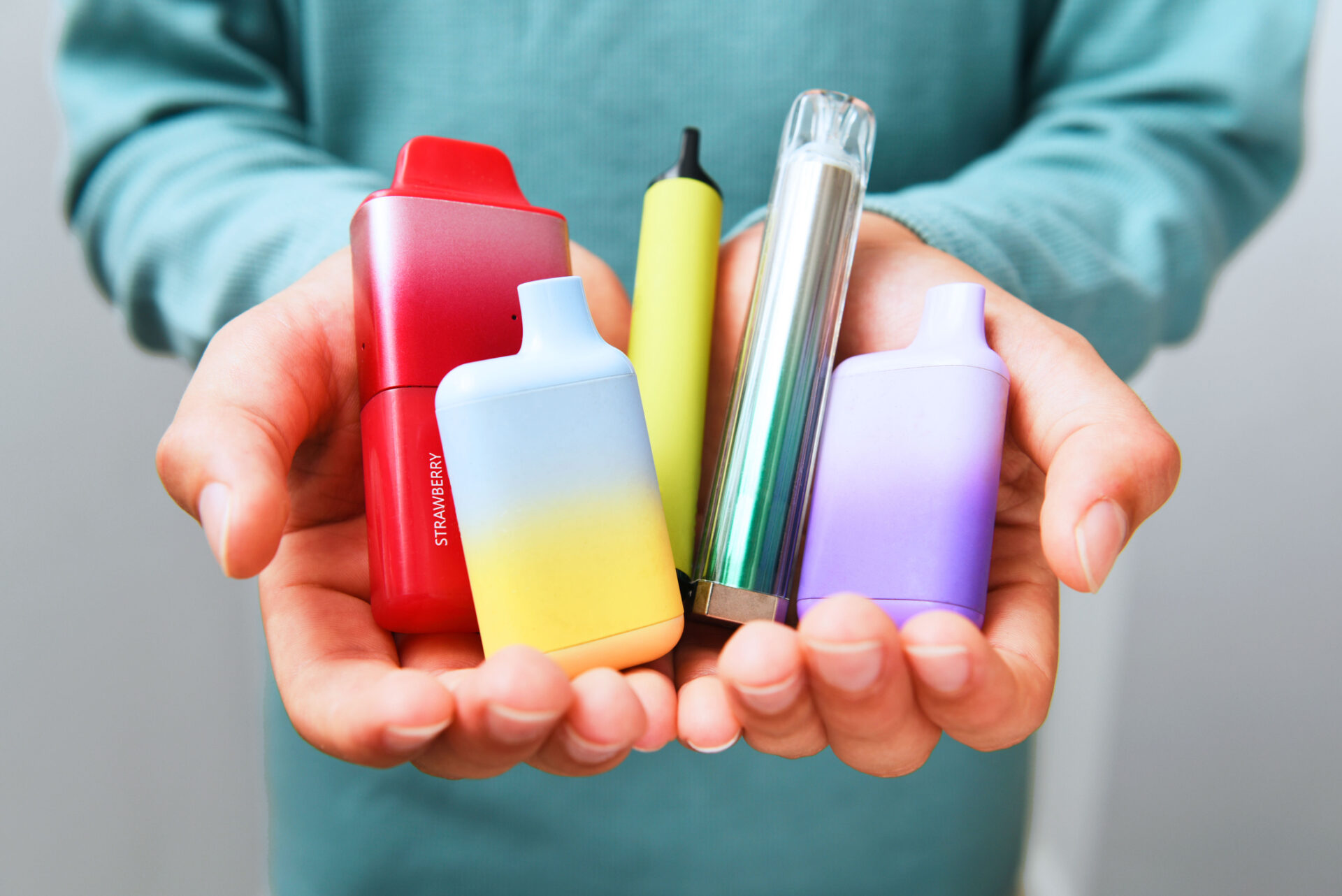 Close up of hands holding a variety of disposable vapes