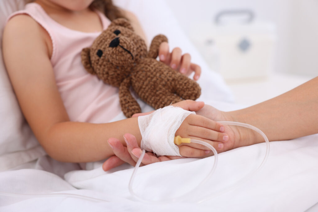 Mother and her little daughter with IV drip on bed in hospital closeup