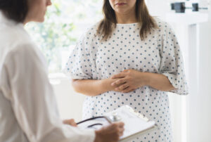 Close up image of a doctor taking notes and a female patient in a hospital gown