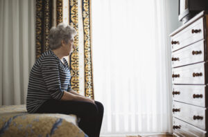 An older woman sat in the corner on her bed