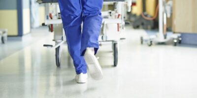 Legs of medic running with gurney along hospital corridor