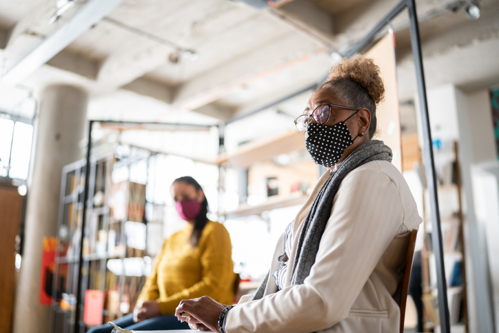 Women sitting in a room apart whilst wearing face masks