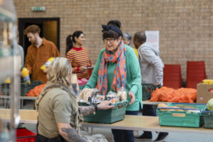 A group of vounteers organising food donations onto tables at a food bank in England.