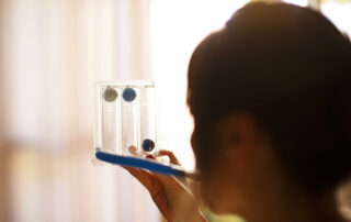 A woman blowing into a device that assist with breathing with COPD