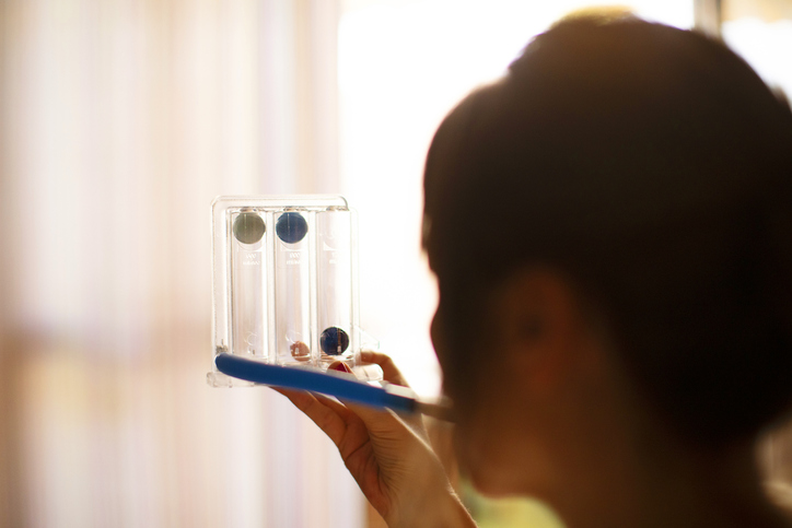 A woman blowing into a device that assist with breathing with COPD